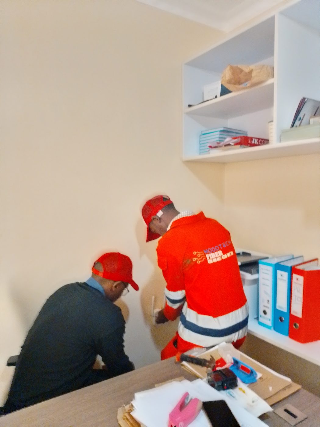 Two ModoTech technicians installing a network point in an office